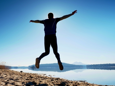 Man crazy jumping on beach.  Sportsman flying on beach during the amazing sunrise above horizonの写真素材