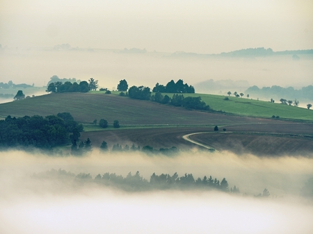Autumn inversion fog. Peaks of hills increased from foggy background.の写真素材