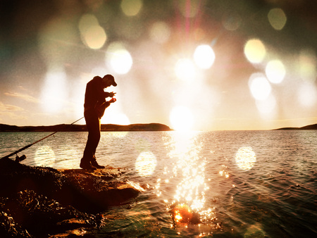 Lens defect. Very close rear view to working fisherman. Man check pushing bait and throws it far into the sea. Fisherman with fishing rodの写真素材