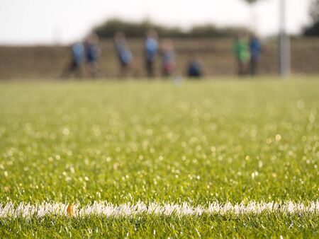 White line marks painted on artificial green turf background. Playfield border. Winter football...