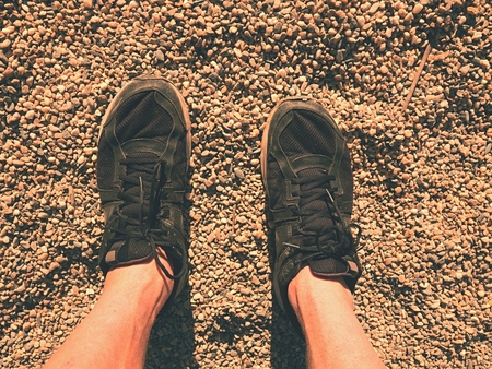 Legs in black sport shoes walking on sandy ground. Man hairy skin legs in running shoesの写真素材