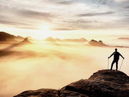 Man silhouette with poles in hand. Sunny spring daybreak and tourist guide stay on sharp cliff of...