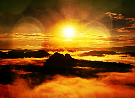 Flare, soft focus. Autumn sunrise forest in a beautiful mountain within inversion. Treetops increased from foggy background.の写真素材