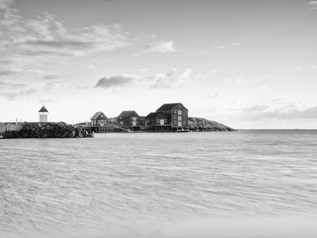 Red houses of the fishing village. Red white buildings  and lighthouse  in small port, coastline of cold north sea, Norway.の写真素材