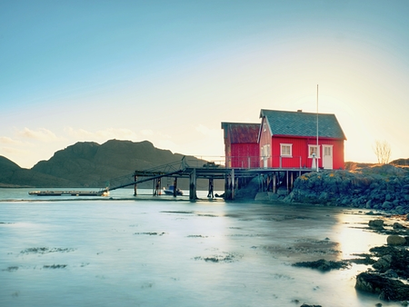Norwegian coast landscape with a typical red house.  Wooden red house on the seaside, first warm spring day.の写真素材