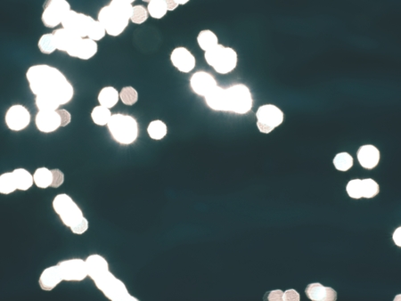 Out of focus bokeh background of blue water with sun reflections. Stars in water levelの写真素材