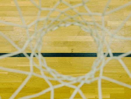 Look through the white string net, hardwood basketball board with black line. Basketball hoop in the sports hall.の写真素材