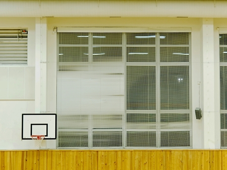 Interior of school gym with walls covered by safety net. Large hall with basketball board high on the wall, renewal interier and brightの写真素材