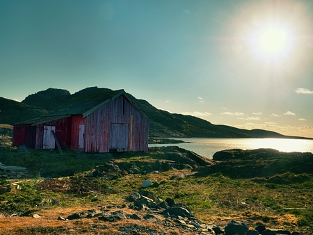 Norwegian coast landscape with a typical red house.  Wooden red house on the seaside, first warm spring day.の写真素材