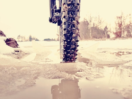 The wheel fell into the muddy puddle while winter mtb trip. Water hidden under snow.の写真素材