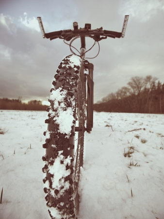 The bicycle wheel in the snow. Detailed extreme close up low ankle view. Snowy filed in ope landscape.の写真素材