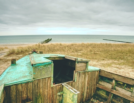 Wrecked wooden fisher boat. Broken abandoned boat in sand of sea bay. Wheatered wood and rusty meat partsの写真素材