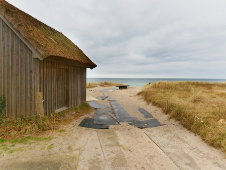 Beach hut at sand dunes, end of road next sea. Old wooden house for fishers.  Overcast dayの写真素材
