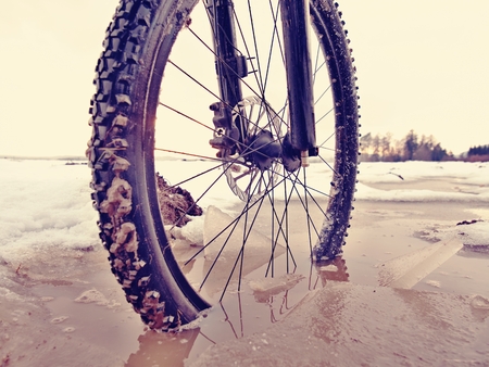 The wheel fell into the muddy puddle while winter mtb trip. Water hidden under snow.の写真素材