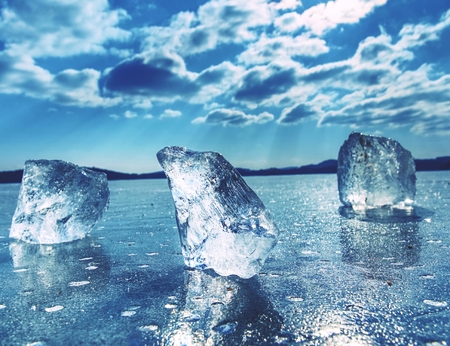 Ice floe at frozen lake surface with reflection. Deep cracks in the ice and ice reflectionの写真素材