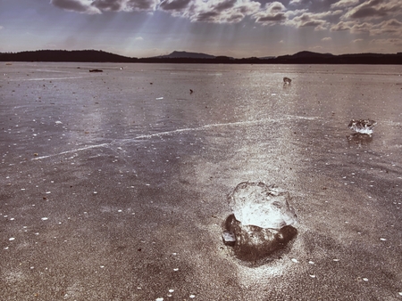 Shining piece of clear ice on frozen lake. Cracks inside many reflections of sun rays. Beauty of winterの写真素材