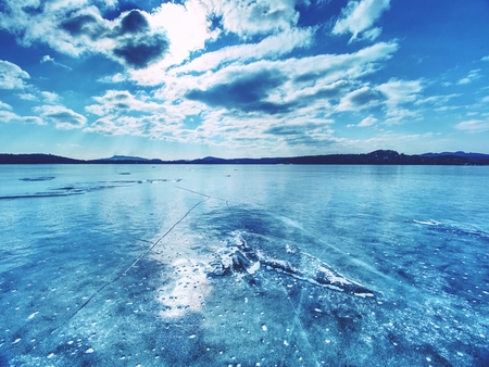 Ice shards on a frozen lake. The rays of the sun creat rainbow shadows in the cracks of the ice.