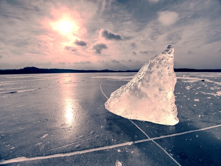 Abstract ice floe on frozen lake, texture of weathered ice and sparkling of evening sun. Deep ice cracks.の写真素材