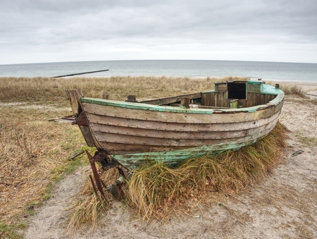 Abandoned wrecked boat stuck in sand. Old wooden boat on the sandy shore of beach. Sunset on the...