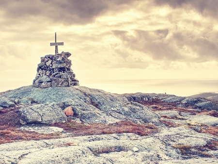 Mountain peak Linesfjellet  (230 m), Linesoya island, Norway. Stone pyramid on mountain summit, swamp and yellow grass. Coudy sky, sunny windy spring day.の写真素材