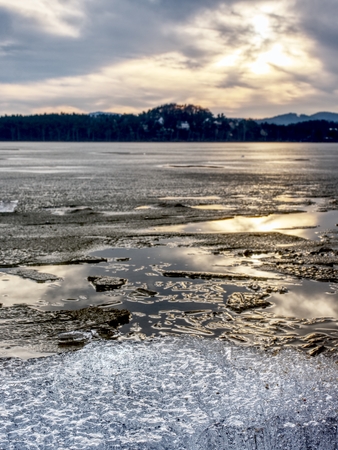 Exposed shore under melting ice. Close up view to border between ice and dark water.  Warm summer on north.の写真素材