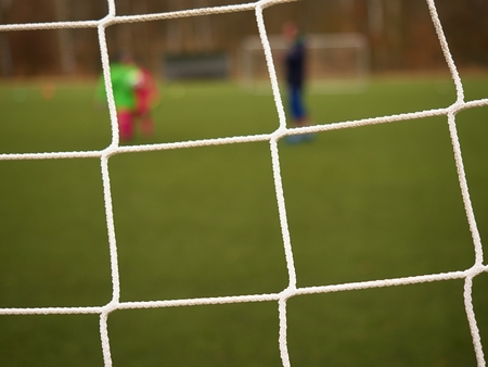Football player stands against goal with net and stadium. Football gate net. Soccer gate net.  In...