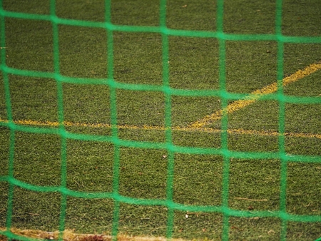 Close up detail of a soccer net against green grass on a cloudy day. Selective focusの写真素材