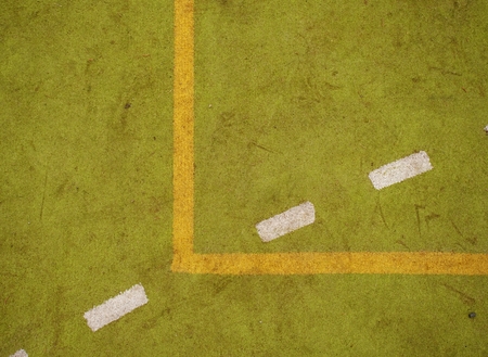 Border lines on court. Worn out green red hairy carpet on outside hanball playground. Floor of...