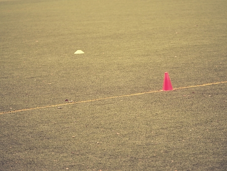 Bright red plastic cone on painted white line of soccer field. Football green playground with  rubber coneの写真素材