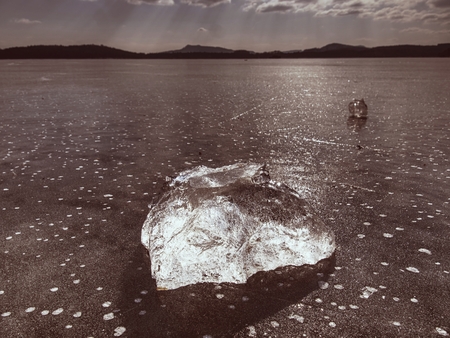 Beautiful transparent piece ice of Lake against dark blue sky and  bright sun.