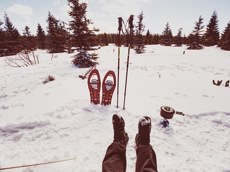 Cooking in front of tent in snow.  Hiker camping in winter mountains.  Man cooking food with portable gas cooker and light dishes. Burning gas stove and in kettle boiling water.  Snowy landscapeの写真素材