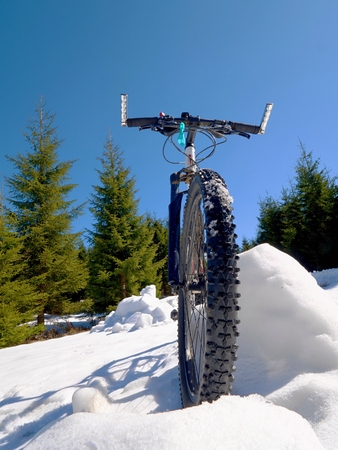 Wide view photo of mountain bike in deep snow. Winter mountains with road lost under snow.の写真素材