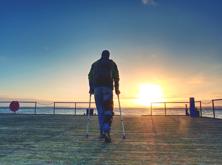 Man goes on the wooden pier in the sunrise. The wharf construction above sea follow  Sun. Fantastic morning with clear sky smooth water levelの写真素材