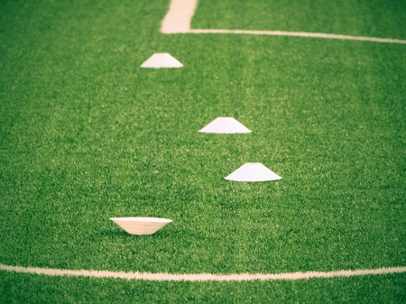 Training cone for football on a green field. Artificial green turf background. Winter football...