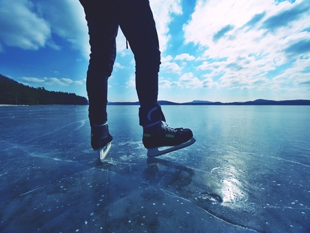 Long male legs in black leggins with hockey skates. Outdoor ice skating on the lakeの写真素材