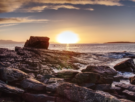 Peaceful dawn at Elgol bay. Low angle  overlooking of offshore rocks and smooth sea, mountains at horizon. Winter  Isle of Skye, Scotland の写真素材