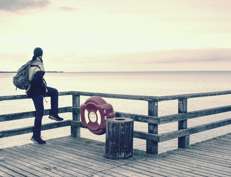 Man traveler on the end of pier watch the far horizon. Moody morning at sea bridgeの写真素材