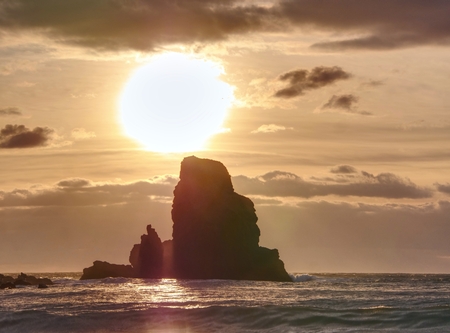 Evening Bay. Sharp rocks, black rounded boulders, stony beach, sand and dark sky.の写真素材