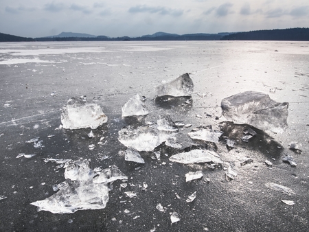 Ice fragments on frozen lake water level. The ice broken into shinning jagged pieces.  Dark natural backlightの写真素材