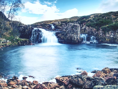 Pools and majestatic waterfalls belllow snowy mountains. Blue water mirrorong blue cloudy skyの写真素材