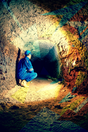 Man worker checking something in abandoned mine tunnel. Underground job. Hipster filter.の写真素材