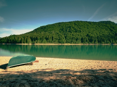 Boat on the shore of a smooth lake in early summer. Beautiful lake landscape with boats on shoreの写真素材