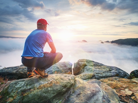 Man observe fall daybreak on peak of rock empire. Dreamy foggy landscape spring orange pink misty sunrise in a beautiful valley of Saxony Switzerland park.の写真素材