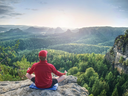 Man meditates in yoga position in mountains above wild nature at sunset. Concept of meditation, spirituality and  soul balanceの写真素材