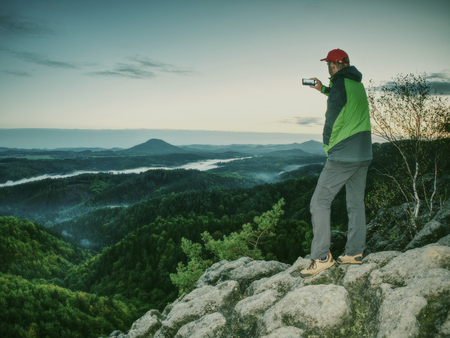 Moment of loneliness. Man on the rock empires and watch over the misty landscapeの写真素材