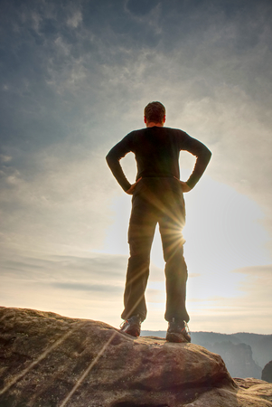 Lone figure watches the sunrise from sharp rock looking down at the wild landscapeの写真素材