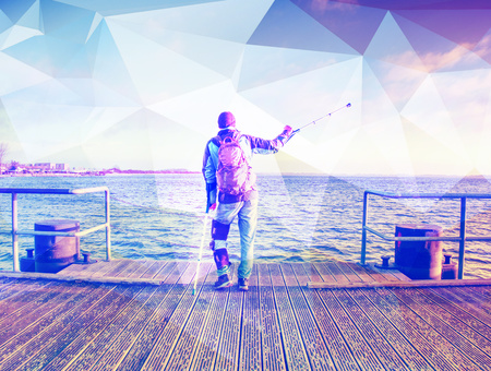 Man goes on the wooden pier in the sunrise. The wharf construction above sea.  Hipster filter.