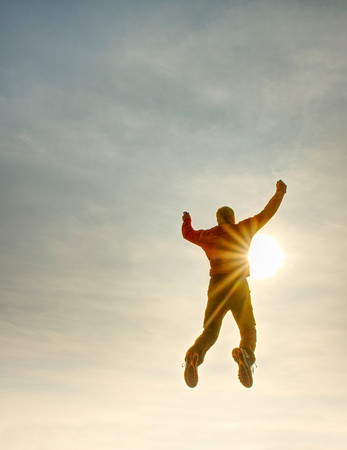 Flying man.  Silhouette of jumping man and sunset sky. Sun flare