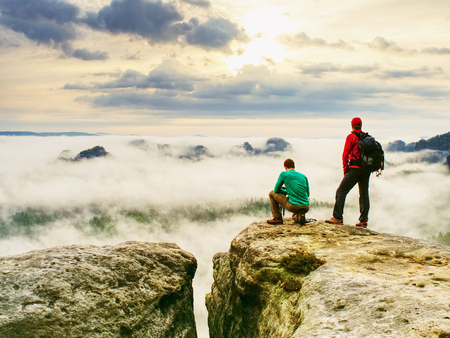 Photographer check weather condition. Freelancer stay with camera on cliff and thinking. Dreamy fogy landscape blue misty sunriseの写真素材