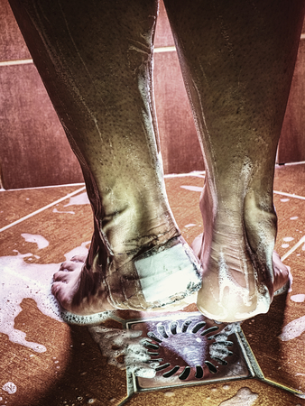 Big plaster cover blister on human heel in shower. Wet bloody painful skin on man foot with adhesive plasterの写真素材